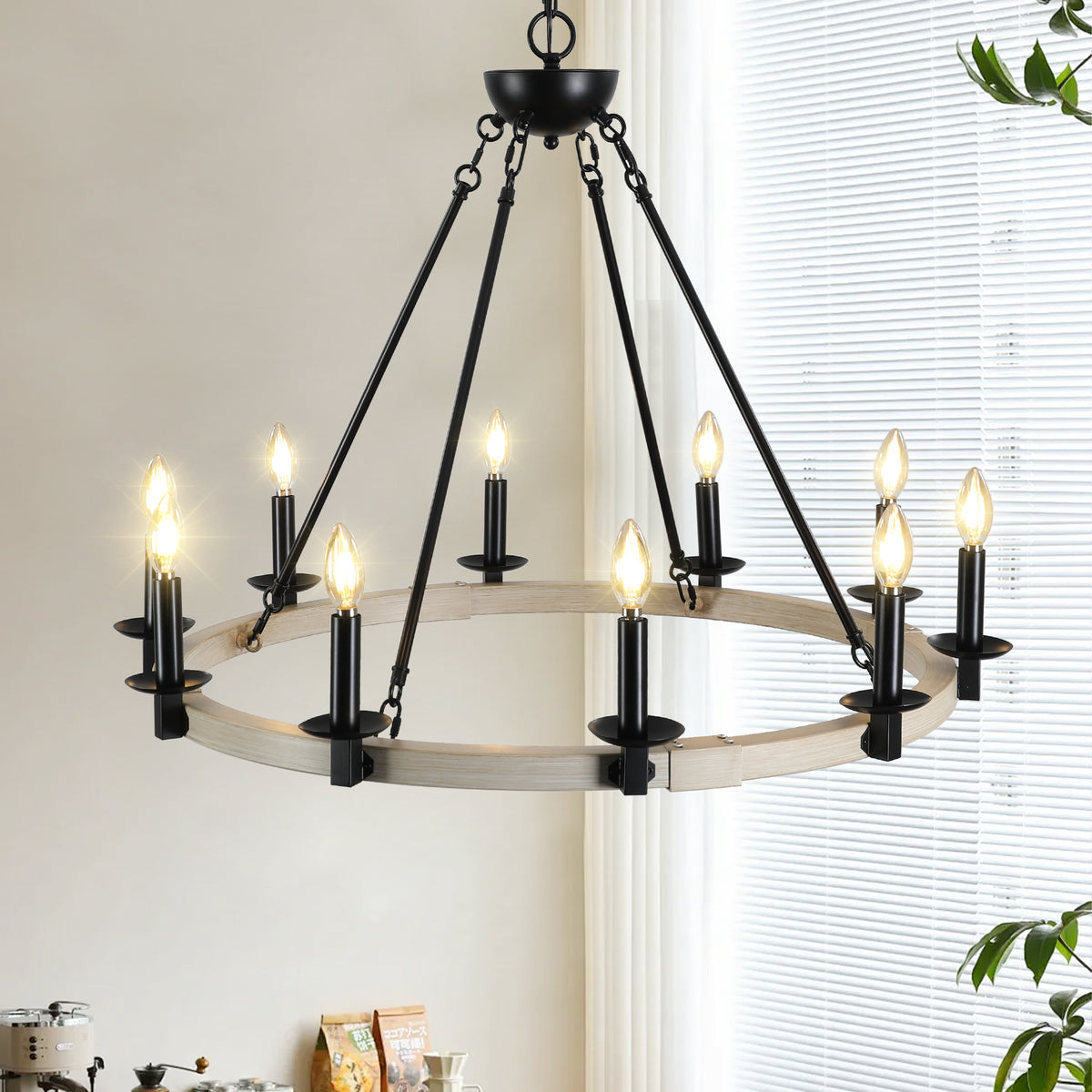 The Ashcombe Round Candle Chandelier featuring a circular iron frame with a rustic white finish and black metal accents, shown against a bright interior background.