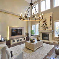 The Ashcombe Round Candle Chandelier hanging in a spacious, modern living room with a fireplace, serving as a focal point for the interior decor.
