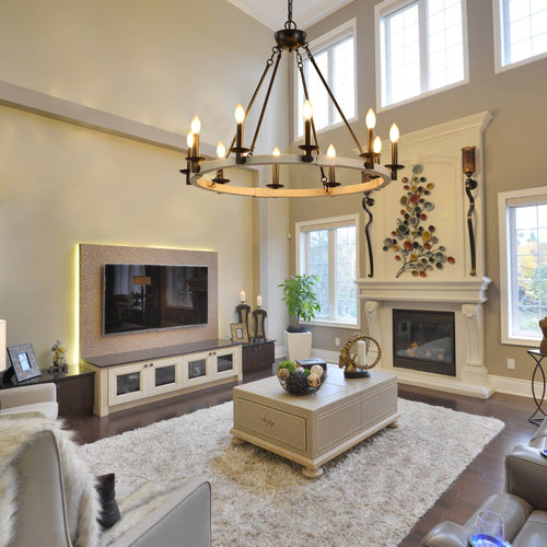 The Ashcombe Round Candle Chandelier hanging in a spacious, modern living room with a fireplace, serving as a focal point for the interior decor.